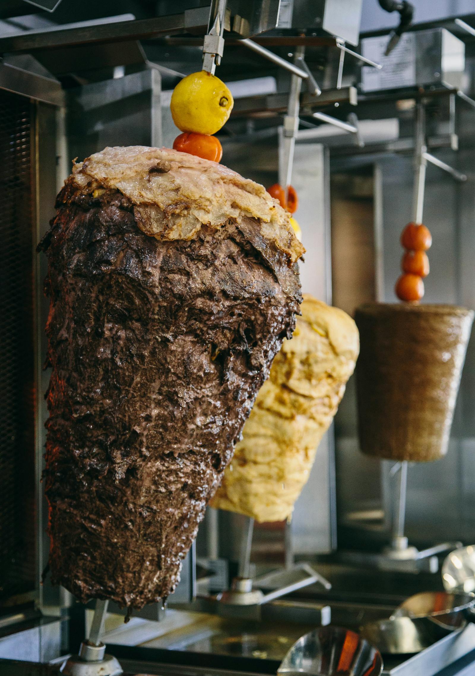 Shawarma roasting on a vertical spit beside warm pita